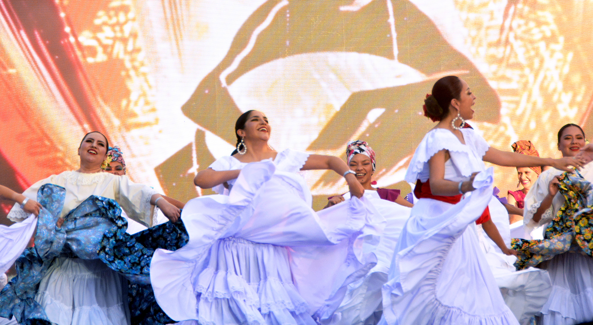 Performers in flowing dresses dance on an outdoor stage at IMMERSE.